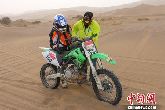 圖為10月19日，拉力賽裁判帶著救援車返回比賽途中，給故障摩托車加油。　耿丹丹 攝